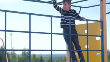 Çocuk parkta ipi tutan bir tırmanma duvarı üzerinde tırmanıyor.