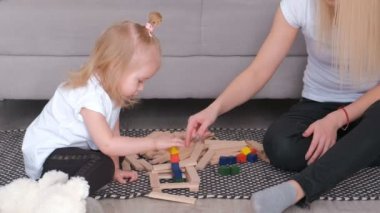 Genç çekici sarışın onunla anne küçük sevimli kızı renkli bloklar bir kuleden bina.