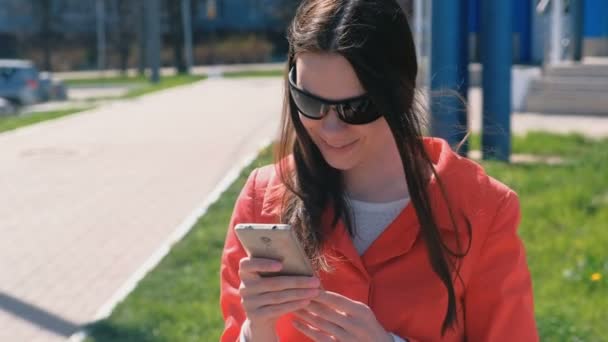 Ritratto di felice accompagnatrice in cappotto rosso aspetta qualcuno e controlla il suo telefono, sms . — Video Stock