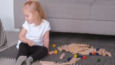 Ahşap bloklar kanepede oturan oynarken küçük sevimli sarışın kız.