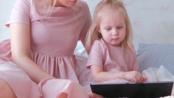 Affascinante bambina bionda che guarda un video su tablet con sua madre . — Video Stock