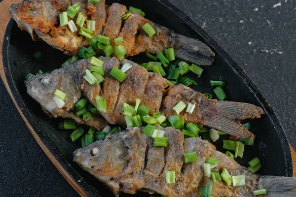 Carpas de peixe fritas em uma bandeja salpicam com cebolas verdes . — Fotografia de Stock