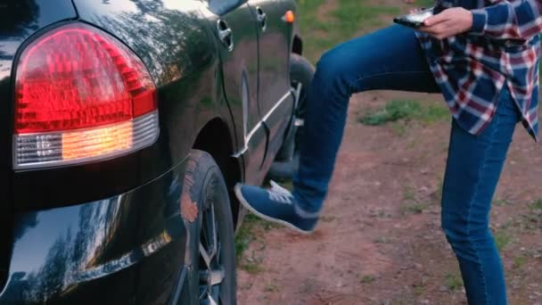 Unrecognazable vrouw schopt het wiel van de auto. Wacht op hulp. — Stockvideo
