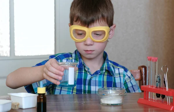 Experimenten op chemie thuis. Boy kijken naar de blauwe vloeistof in het bekerglas. — Stockfoto