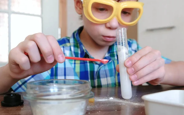 Experimentos de química en casa. Reacción química con la liberación de gas en el tubo de ensayo en las manos del niño . — Foto de Stock