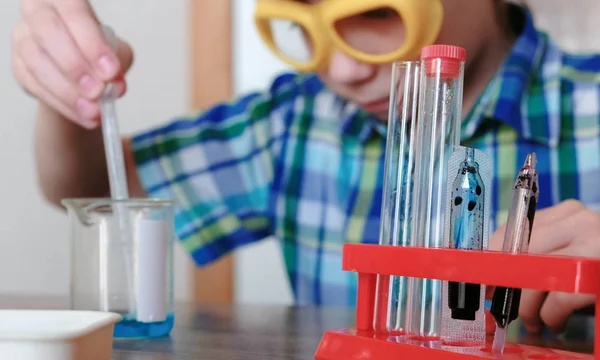 室内化学实验。男孩用吸管将烧杯中的蓝色液体倒入管内。. — 图库照片
