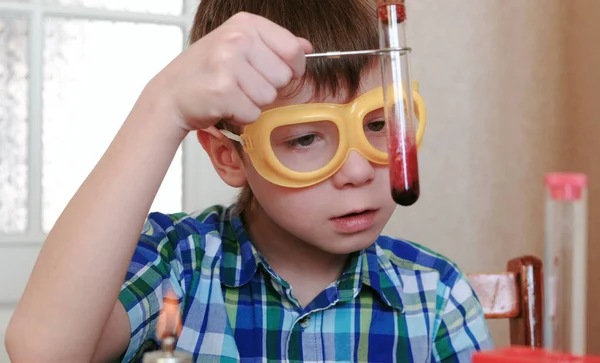 Experimentos de química en casa. Boy examina el contenido del tubo de ensayo . —  Fotos de Stock