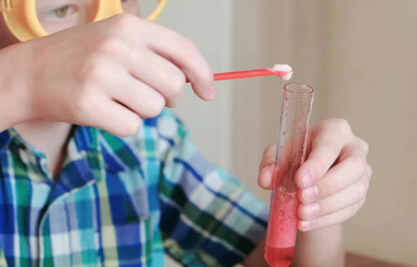 Πειράματα στη χημεία στο σπίτι. Αγόρι χύνει μια σκόνη σε χημική αντίδραση με την απελευθέρωση του αερίου στο δοκιμαστικό σωλήνα. — Φωτογραφία Αρχείου