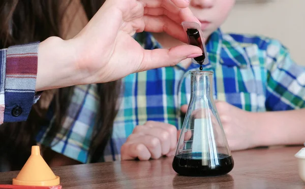 Scheikundige experimenten thuis. Vrouw druipt de verf in de kolf of fles met de vloeistof. — Stockfoto