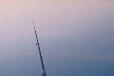 Gün batımında balık tutma. Olta gölet üzerinde.