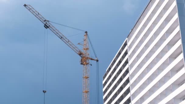 Uppförandet av en byggnad i flera våningar. Hus och konstruktion kran på himmel bakgrund. — Stockvideo