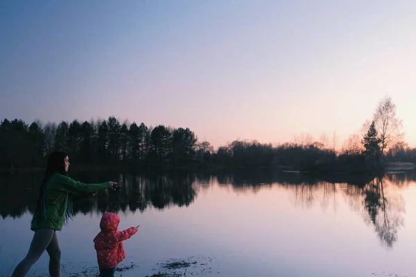 Mãe e filha de pesca no lago ao pôr do sol à noite . — Fotografia de Stock