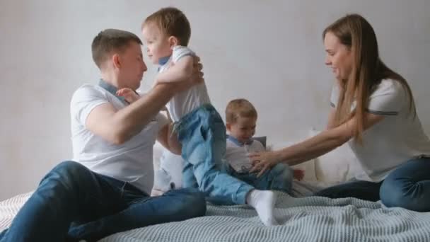 Mamá y papá juegan con los niños gemelos tumbados en la cama. Día libre en familia . — Vídeos de Stock