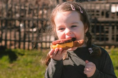 Genç Sevimli küçük kız pirzola ve peynirli sandviç yiyor.