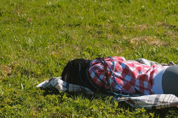 Mujer irreconocible con trenzas africanas azules durmiendo en el césped del parque . —  Fotos de Stock