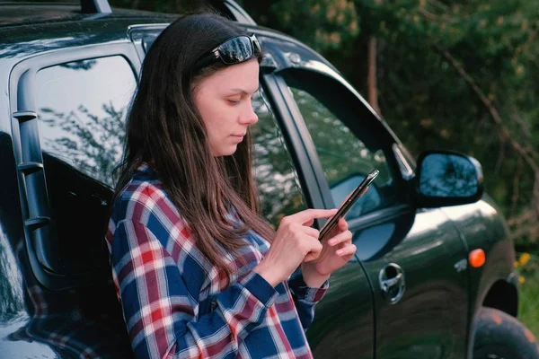 Mujer envía un mensaje en el teléfono de pie junto al coche . — Foto de Stock