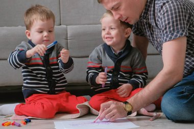 Aile Baba ve iki ikiz erkek kardeşleri birlikte işaretleri çizmek ve kalemler katta oturan hissettim