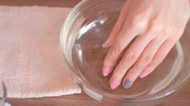 Evde Manikür. Kadın elini su bir kase daldırma. El yakın çekim.