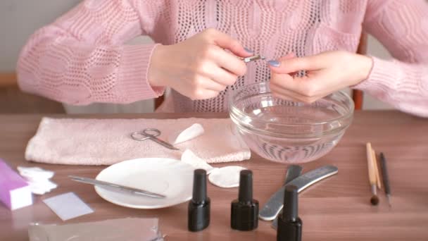Donna taglia cuticola con pinza. Si fa la manicure da sola. Mani in alto. Utensili per manicure sul tavolo . — Video Stock