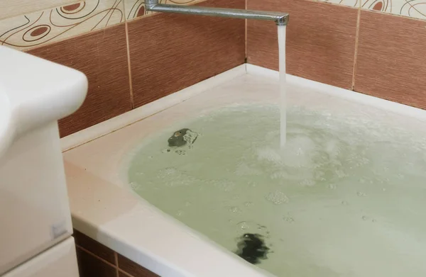 Strong stream of water pours into the tub. Water pours out. Tub overflows. Close up.