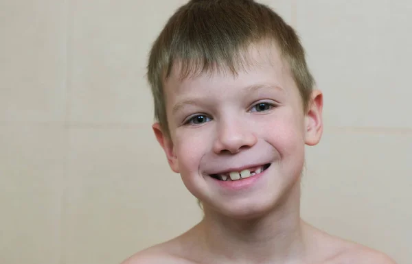 Niño de siete años sobre un fondo claro mirando a la cámara, sonriendo. Primer plano . — Foto de Stock