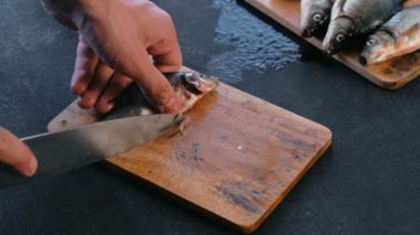 Adam balık sazan yüzgeçleri keser. Balık pişirme. Eller yakın çekim.