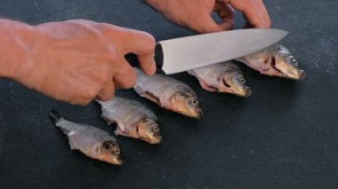 Adam siyah masada sazan balık kesim yapar. Balık pişirme. Yakın çekim el.