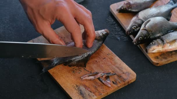 O homem corta as barbatanas do peixe carpa em tábua de madeira. A cozinhar peixe. Mãos ao alto . — Vídeo de Stock