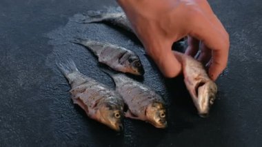 Adam masaya carps balık döner ve baharatlarla sprinkles. Balık pişirme. El yakın çekim.