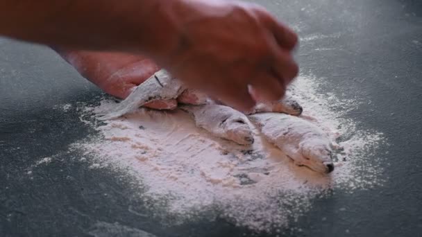 L'uomo prende il pesce in farina dalla tavola in mano. Cucinare il pesce. Mani in alto . — Video Stock