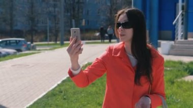 Video: mavi sokakta bina yanında telefon çağrı konuşurken güneş gözlüğü genç esmer kadın.