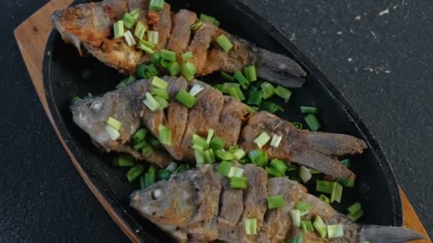 Carpas de pescado frito en una bandeja espolvorear con cebollas verdes . — Vídeos de Stock