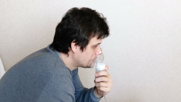 Use nebulizador e inhalador para el tratamiento. Hombre joven inhalando a través de la máscara del inhalador. Vista lateral . — Vídeo de stock