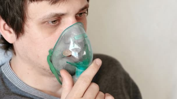Use nebulizer and inhaler for the treatment. Closeup mans face inhaling through inhaler mask. Front view. — Stock Video