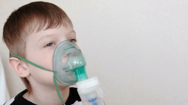 Use nebulizer and inhaler for the treatment. Boy inhaling through inhaler mask. Front view. — Stock Video