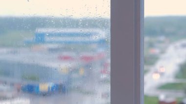 Yağmur damlaları akış aşağı pencere yakın çekim. Çok bina evin ıslak penceresinden görüntülemek, bulanıklık
