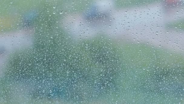 Regentropfen fließen aus nächster Nähe durch das Fenster. Sicht auf Dichte und Straße aus nassem Fenster, Unschärfe. — Stockvideo