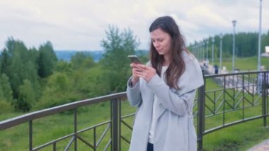 Sohbet, promenade City boyunca yürüyüş cep telefonunda bir mesaj yazarak genç esmer kadın.