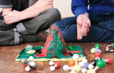 Mom and sons hands make experience with plasticine volcano at home. Chemical reaction with gas emission. clipart