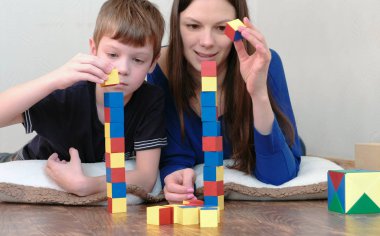 Bir kule bloklarla inşa. Anne ve oğlu yerde yatarken ahşap renkli eğitim oyuncak blokları ile birlikte oynarken