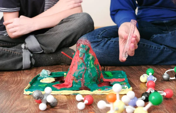 Mom and sons hands make experience with plasticine volcano at home. Chemical reaction with gas emission. — Stock Photo, Image