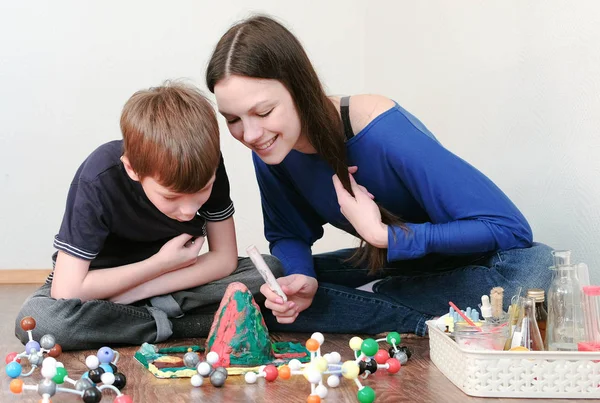 Mom and son looking at chemical reaction with gas emission. Experience with plasticine volcano at home. — Stock Photo, Image