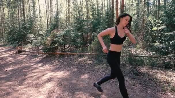 La mujer en ropa deportiva está corriendo en el parque. Se detuvo para recuperar el aliento. Vista lateral. Movimiento lento . — Vídeos de Stock