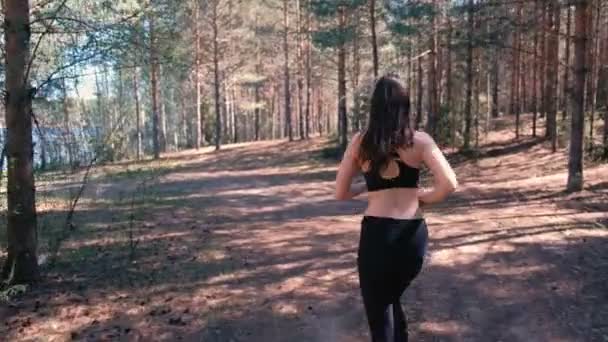 La mujer en ropa deportiva está corriendo en el parque junto al lago. Movimiento lento . — Vídeos de Stock