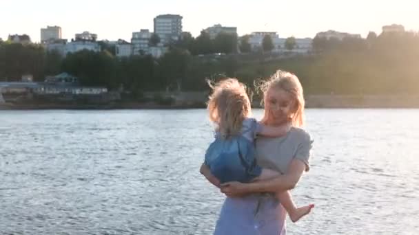 Mother and daughter on the river in the city. Mother spinning with her daughter in her arms. — Stock Video