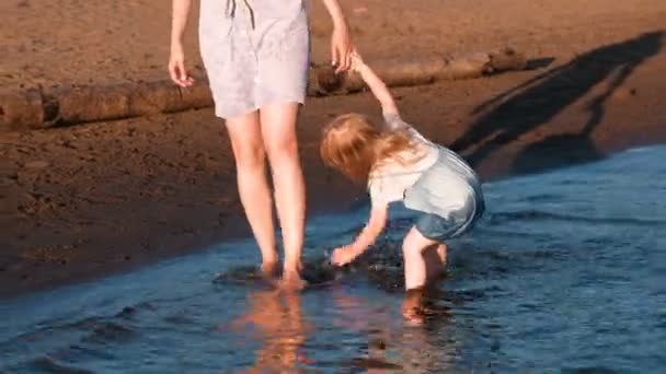 Мама и девочка играют на пляже реки на закате и плавают . — стоковое видео