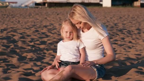 Vacker blond mamma och dotter spela med sand som sitter tillsammans på stranden. — Stockvideo