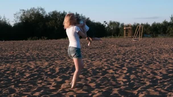 Мати і дочка на пляжі. Мати крутиться з дочкою на руках . — стокове відео
