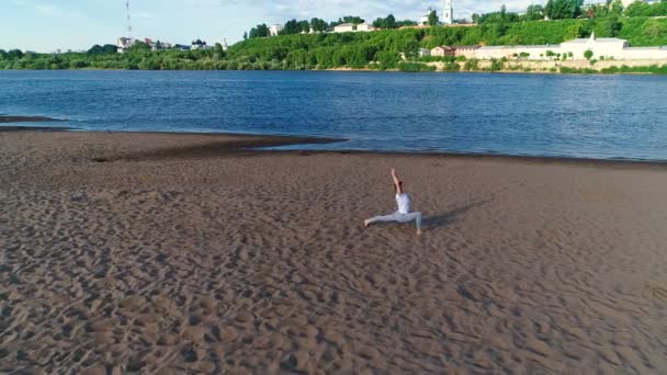 Şehrin nehir kenarında kumsalda yoga yaparken kadın. Harika bir manzara. — Stok video