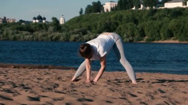 Şehrin nehir kenarında kumsalda Yoga esneme kadın. Harika bir manzara.